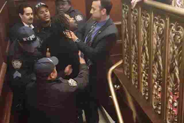 Henry surrounded by NYPD officers after being removed from the chamber